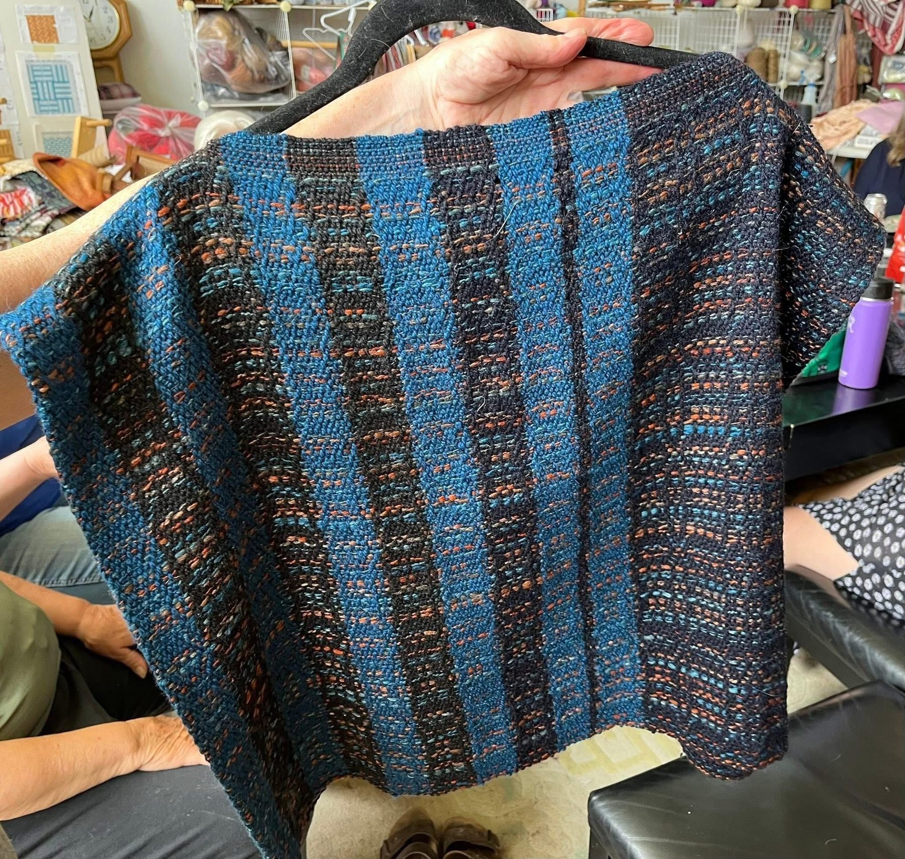 Blue and teal striped handwoven poncho on a mannequin